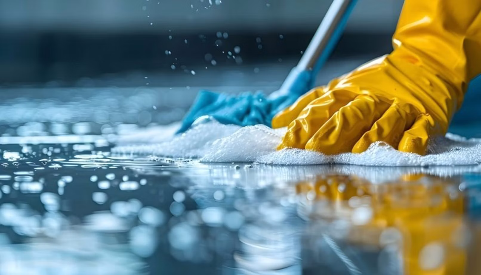 Gloved cleaner wiping a soapy surface with a cloth
